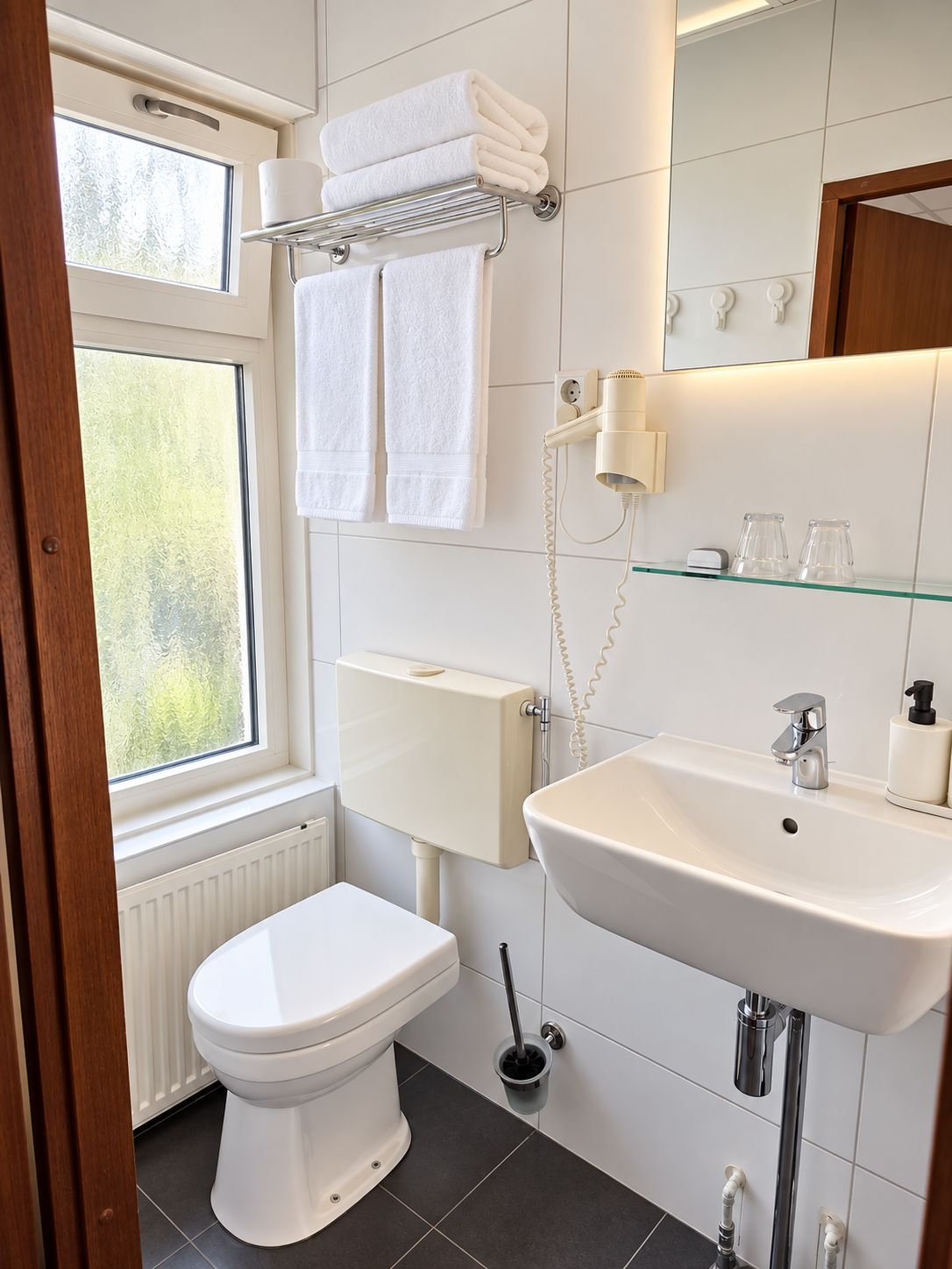 Un baño moderno con inodoro, lavamanos y perchero para toallas.