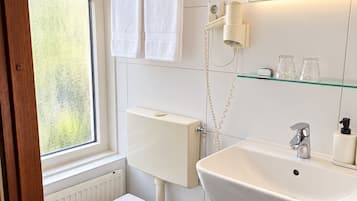 Un baño moderno con inodoro, lavamanos y perchero para toallas.