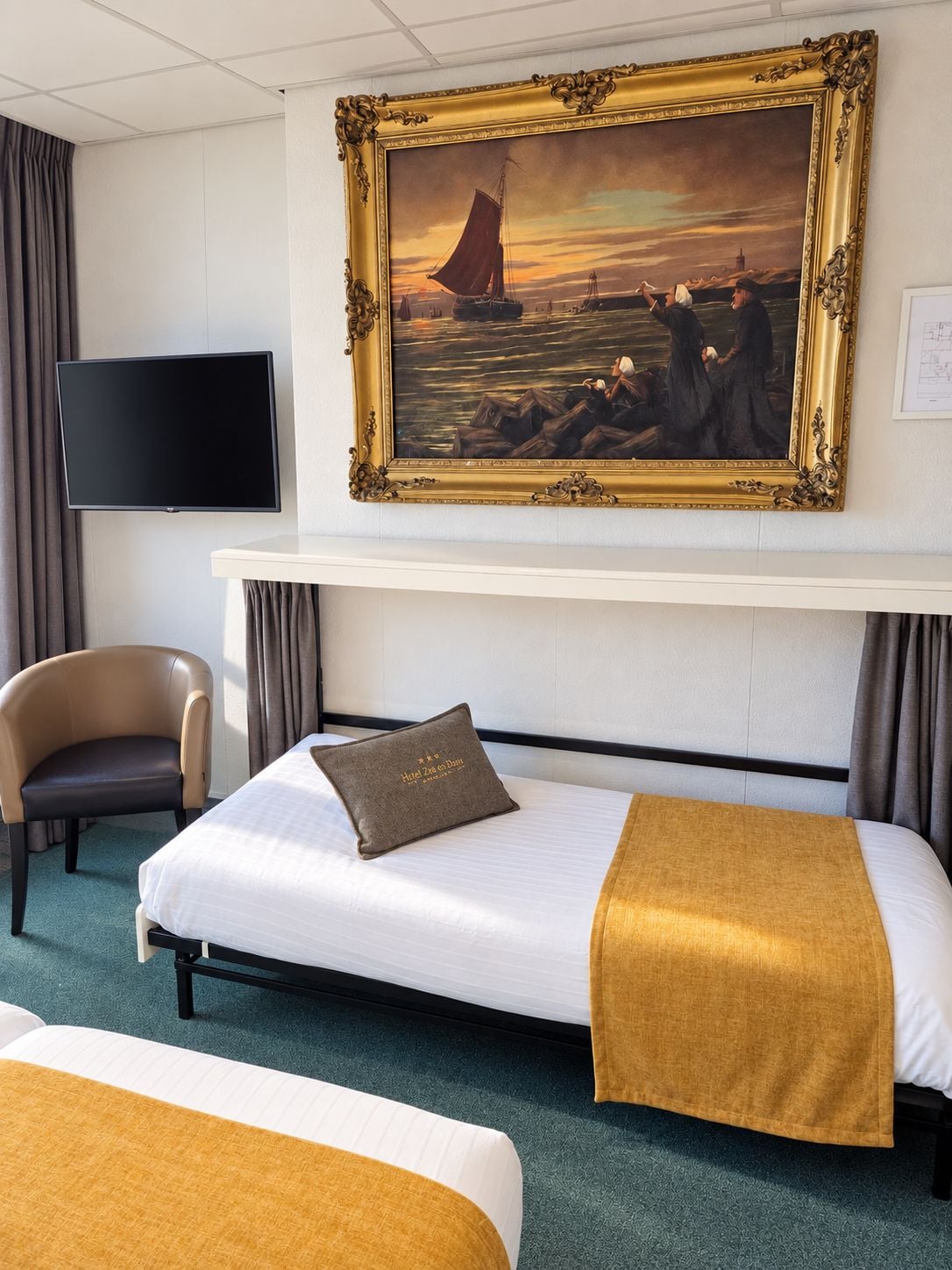 Een hotelkamer met een bed, een stoel, een televisie en een schilderij aan de muur.
