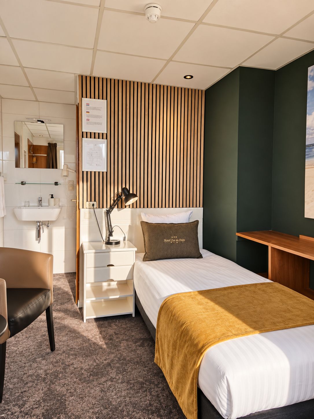 Une chambre d’hôtel avec un lit, une table de chevet, une lampe et une vue sur la mer.
