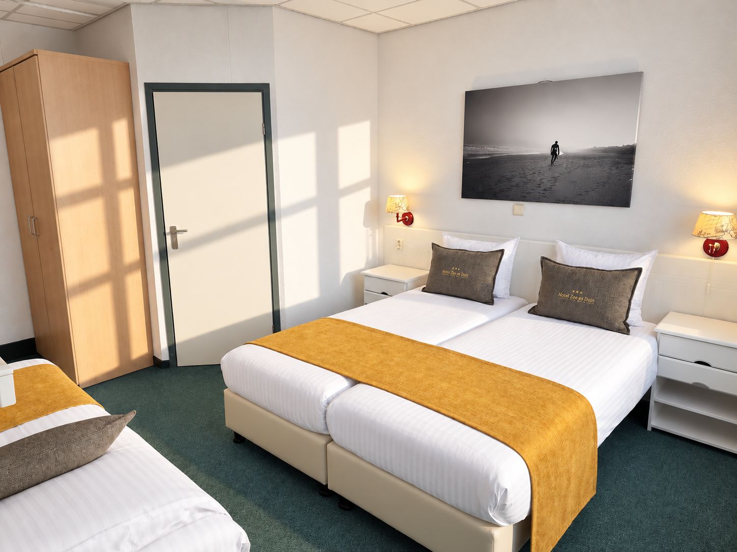A hotel room with a large bed, two bedside tables, a wardrobe, and a wall-mounted picture.