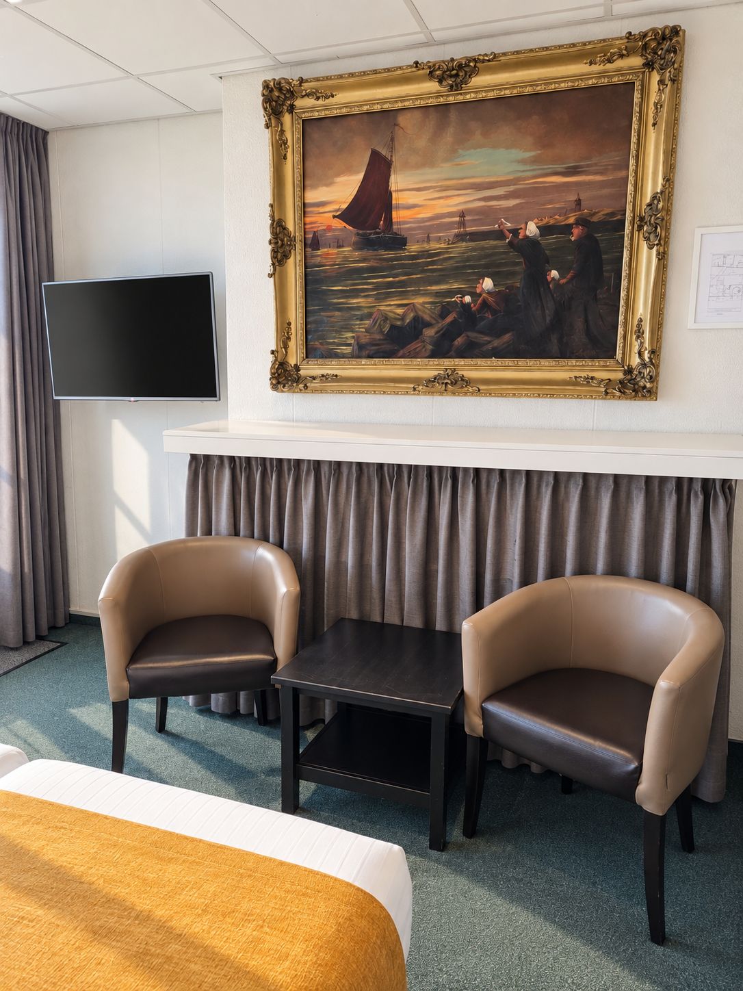 Une chambre d’hôtel avec un tableau, deux chaises, une table, un lit et un téléviseur à écran plat.