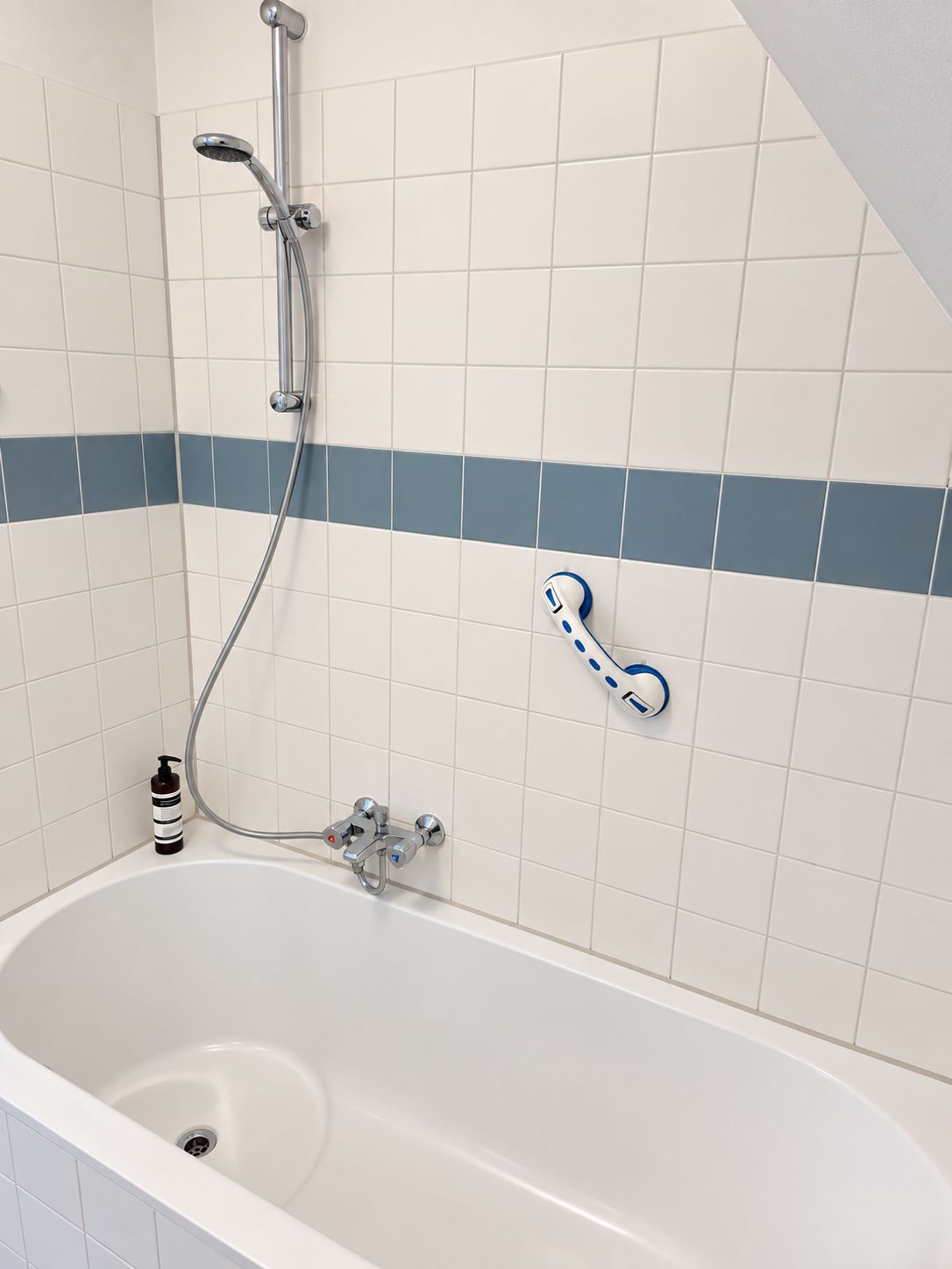 Een badkamer met een bad, een douchekop en een handdoekhouder.