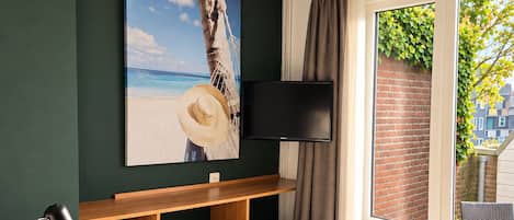 A hotel room with a bed, a desk, a chair, a television, and a window with a view of the outside.