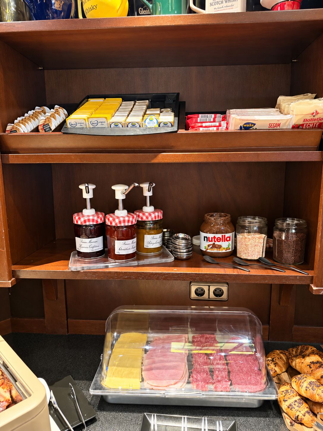 Eine Küchenarbeitsplatte mit verschiedenen Lebensmitteln, darunter Marmeladengläser, Nutella und Brot.