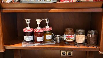 Eine Küchenarbeitsplatte mit verschiedenen Lebensmitteln, darunter Marmeladengläser, Nutella und Brot.