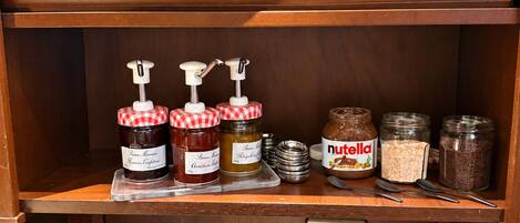 Un plan de travail de cuisine avec divers aliments, notamment des pots de confiture, du Nutella et du pain.