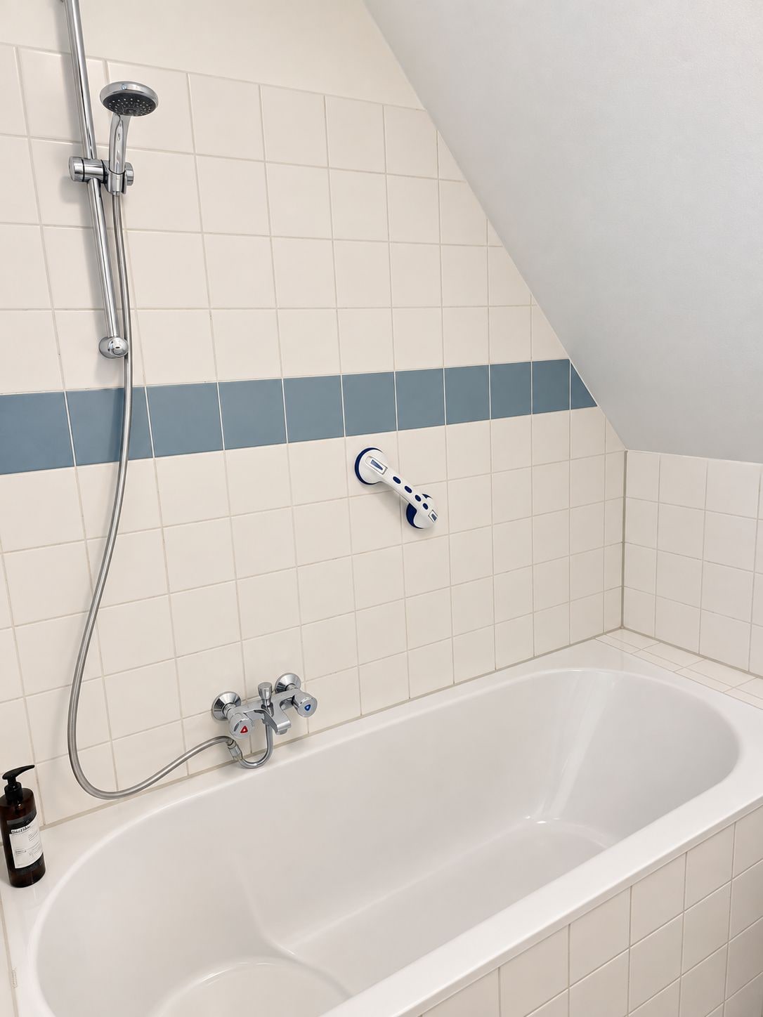 Een badkamer met een bad, een handdouche en een massageapparaat.
