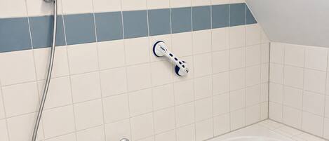 A bathroom with a bathtub, a handheld showerhead, and a handheld massager.