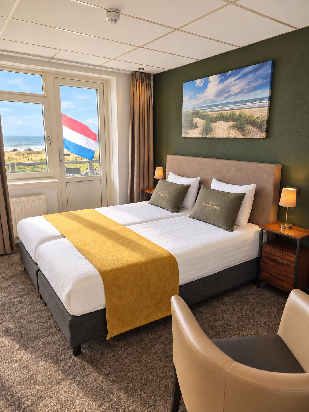 A hotel room with a bed, a view of the beach, and a flag.