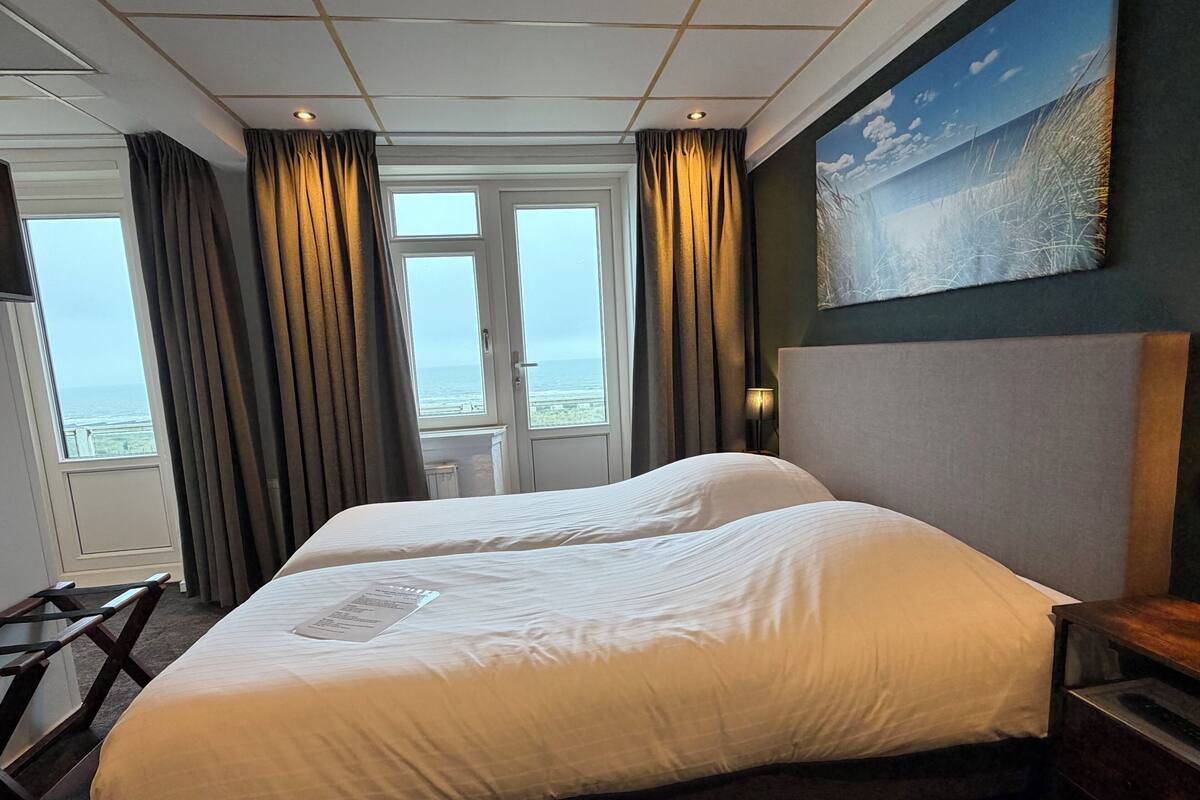 Habitación de hotel con una cama grande, un escritorio, una silla, un cuadro y vistas al mar.