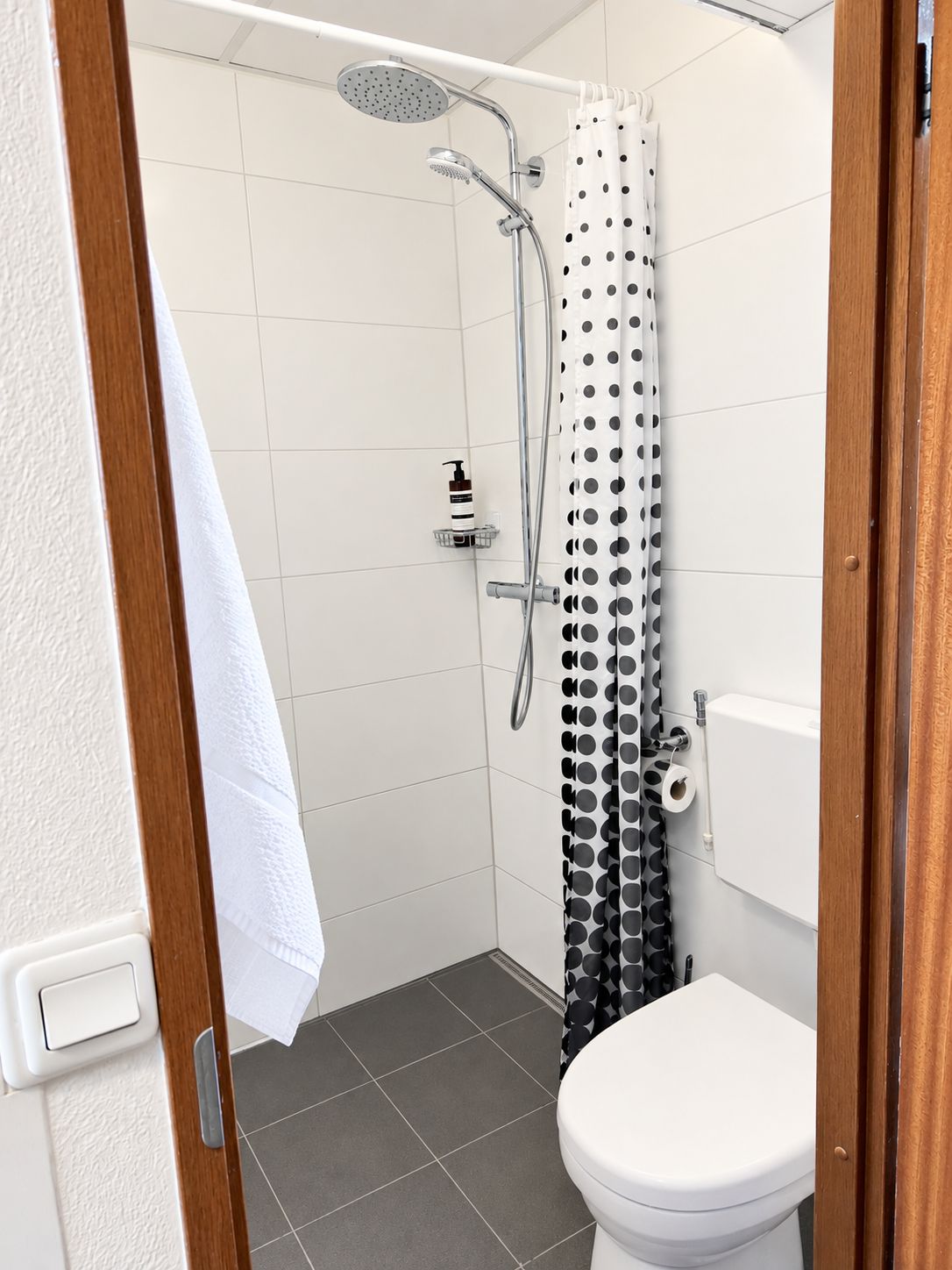 Een badkamer met een douche, toilet en een handdoekhouder.