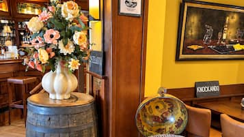 Een bar met een vat waarop 'GLENROTHL'S' staat en een decoratieve stoel met een fruitmand.