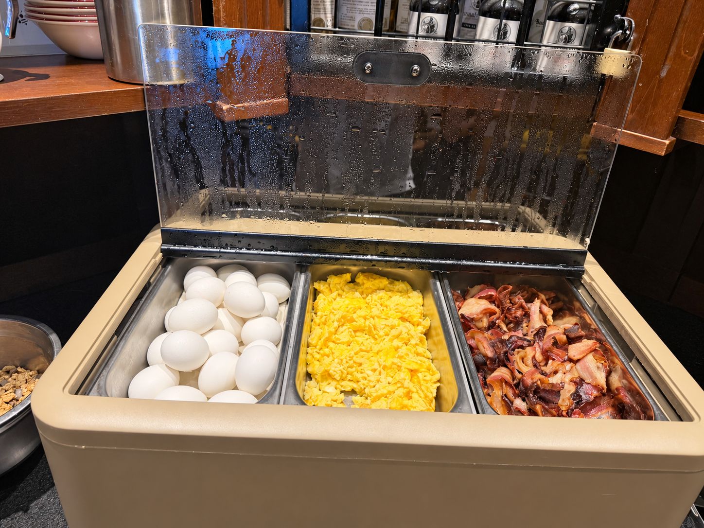 A breakfast buffet with eggs, scrambled eggs, and bacon.