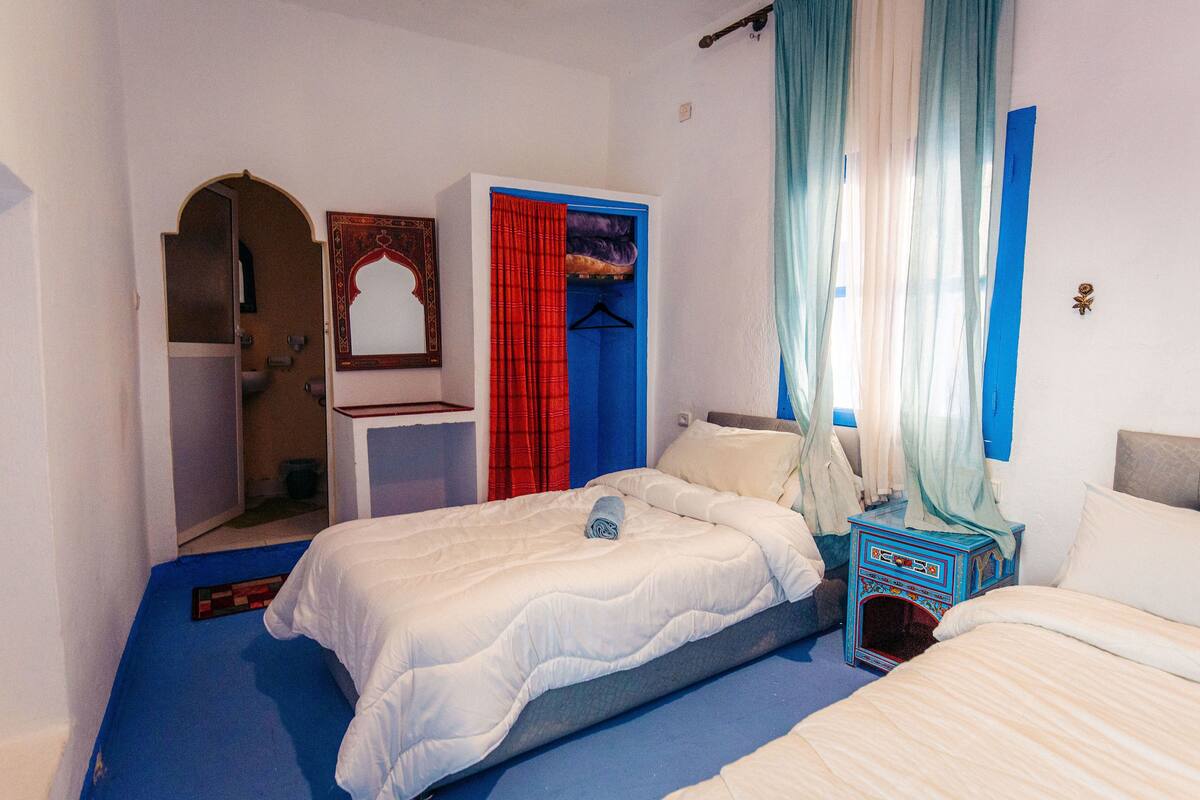 Une chambre à coucher avec un lit, une armoire, un miroir et une petite table.