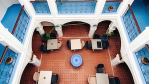 Un atrium à plusieurs niveaux, doté d’un espace de repos central, de rampes bleues et d’un luminaire suspendu.
