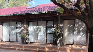 A building with a red-tiled roof, brick walls, and large windows. There are potted plants on the ground floor. - 8 Soenie Avenue Self Catering (Akasia)