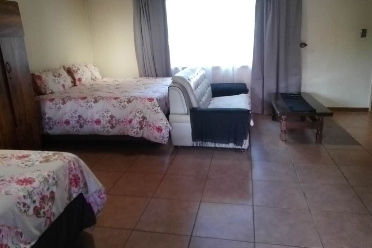 Una habitación con dos camas, un banco y una ventana con cortinas.