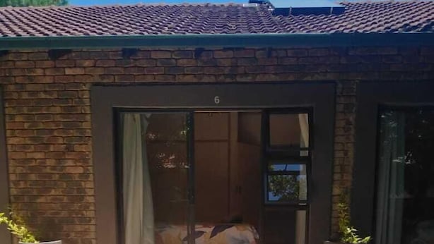 A building with a brick exterior, a numbered door, and potted plants. - 8 Soenie Avenue Self Catering (Akasia)