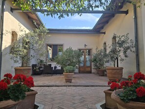 A courtyard with potted plants, a wooden door, and a tiled floor. - La Primavera B&B (Volterra)