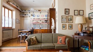 Una sala acogedora con un sofá de cuadros, una mesa de comedor y una cocina al fondo.