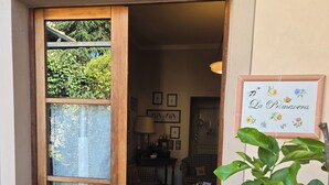 Una puerta de madera con un panel de vidrio, un letrero que dice 'La Primavera', y una vista de un cuarto con un sofá y una mesa.