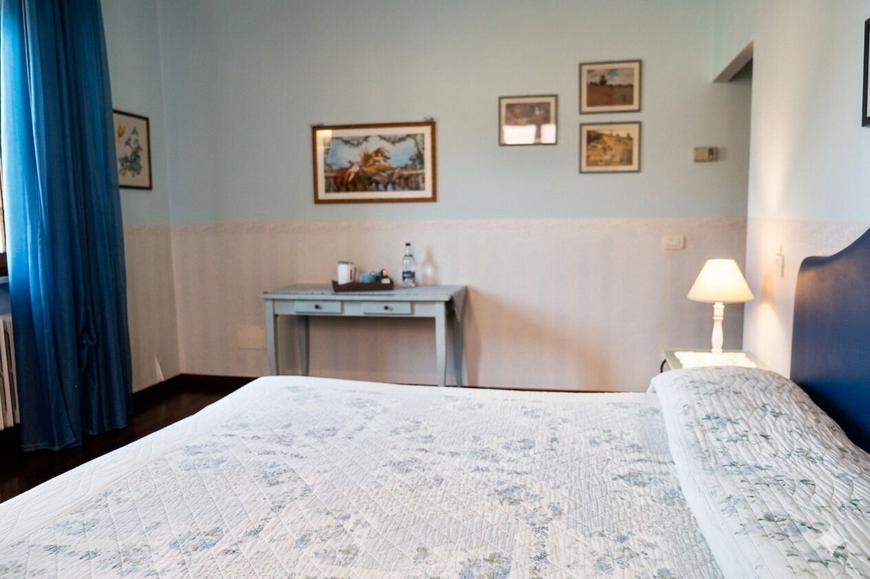 Ein Hotelzimmer mit einem Bett, einem Schreibtisch, einer Lampe und Wandbildern.
