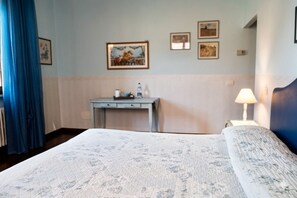 A hotel room with a bed, a desk, a lamp, and wall art. - La Primavera B&B (Volterra)