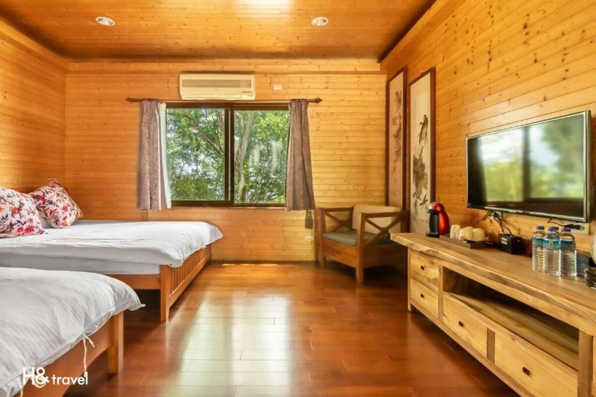 A wooden cabin room with two beds, a TV, and a desk with a chair.
