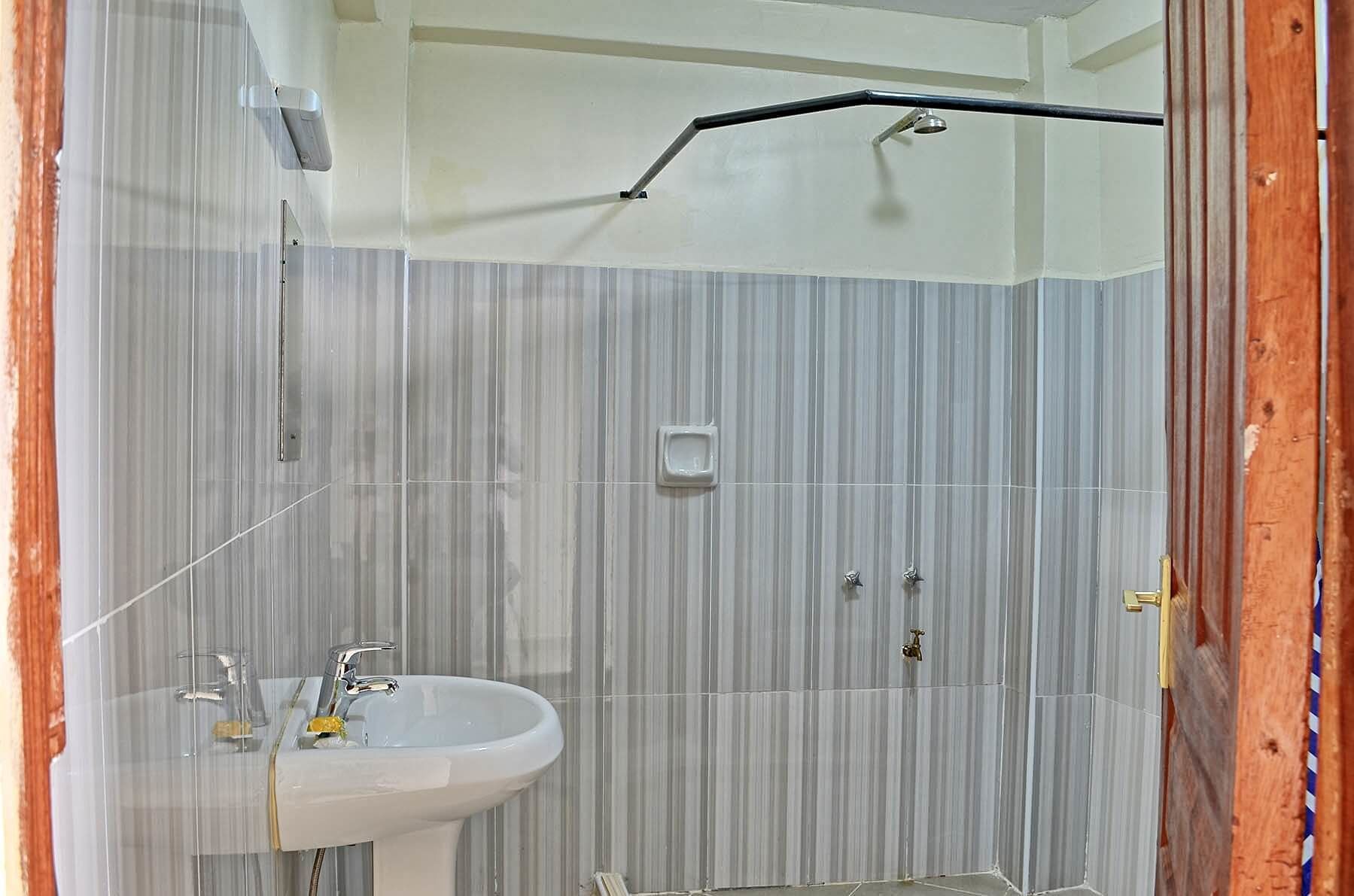 A bathroom with a sink, mirror, and shower.