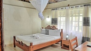 Un lit en bois avec un baldaquin, une table de chevet, une chaise et des rideaux à motifs de girafe.