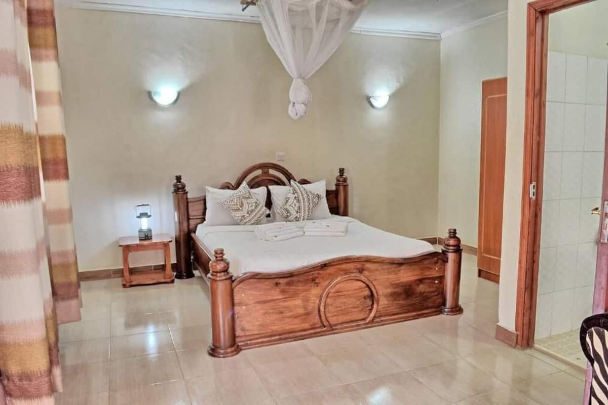 Quarto com cama de madeira, luminárias de cabeceira e dossel.