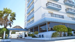 A multi-story hotel with balconies, a covered entrance, and a parking area. - Hotel Solmar (San Clemente)