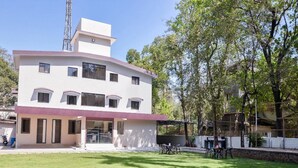 Um edifício de vários andares com telhado plano, um alpendre coberto e um gramado bem cuidado.