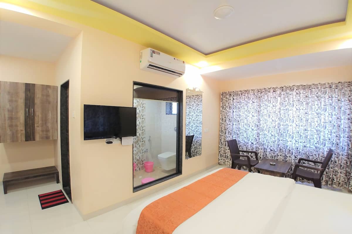 A hotel room with a bed, a TV, a mirror, a desk, and a chair.