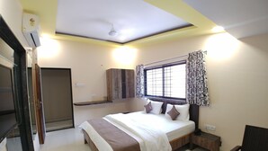 Quarto com cama, mesa de cabeceira e janela com cortinas.