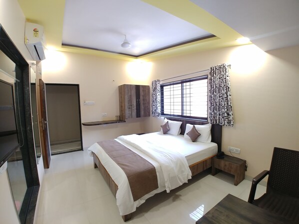 A bedroom with a bed, bedside table, and a window with curtains.