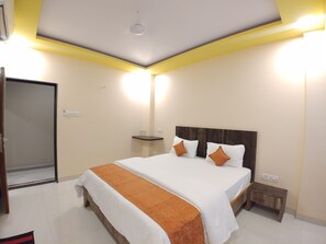 A hotel room with a large bed, bedside tables, a wardrobe, and a ceiling light fixture. - Hotel Mangal Residency (Mawal)