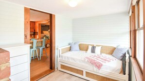 Ein gemütliches Schlafzimmer mit Bett, Essbereich und einer durchgehenden Tür erkennbaren Küche.