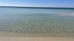 A beach with clear shallow water and a sandy shore.