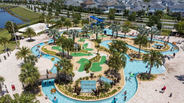 A large outdoor swimming pool area with multiple lanes, palm trees, and a water slide. - Single Family Home @ Storey Lake Resort Vacation Homes in Kissimmee...!!! (Kissimmee)