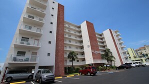 Un hotel de varios pisos con balcones y un estacionamiento.