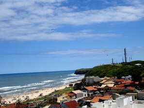 A coastal town with a beach, houses, and a hill with a lighthouse. - Excellent beachfront apartment, two blocks from the beach. (Torres)