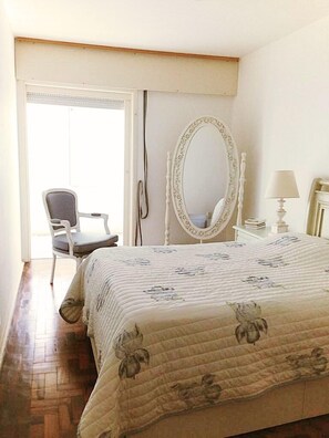A bedroom with a bed, a chair, a vanity with a mirror, and a lamp. - Excellent beachfront apartment, two blocks from the beach. (Torres)