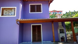 Ein zweistöckiges Gebäude mit violetten Wänden, einer Holztür und Fenstern mit Fensterläden.