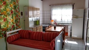 Eine kompakte Küche mit Essbereich, einer Couch und einem Fenster mit Vorhängen.