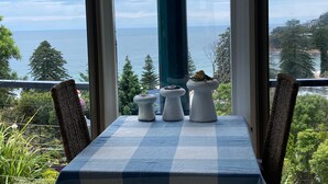 Un balcon avec une table dressée pour deux personnes, offrant une vue sur la côte.