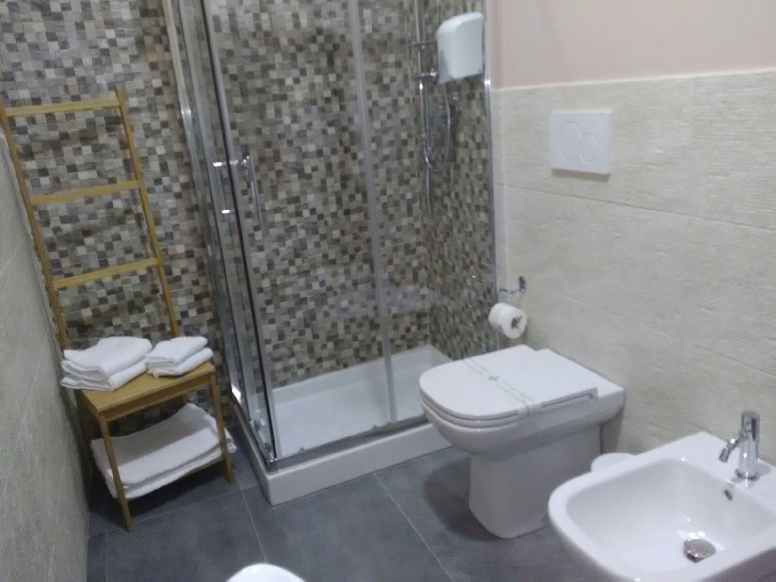 A bathroom with a glass shower enclosure, a toilet, and a sink.