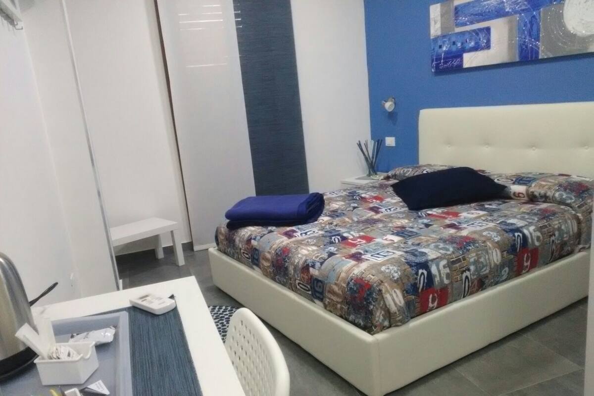 A bedroom with a bed, a desk, and a chair.