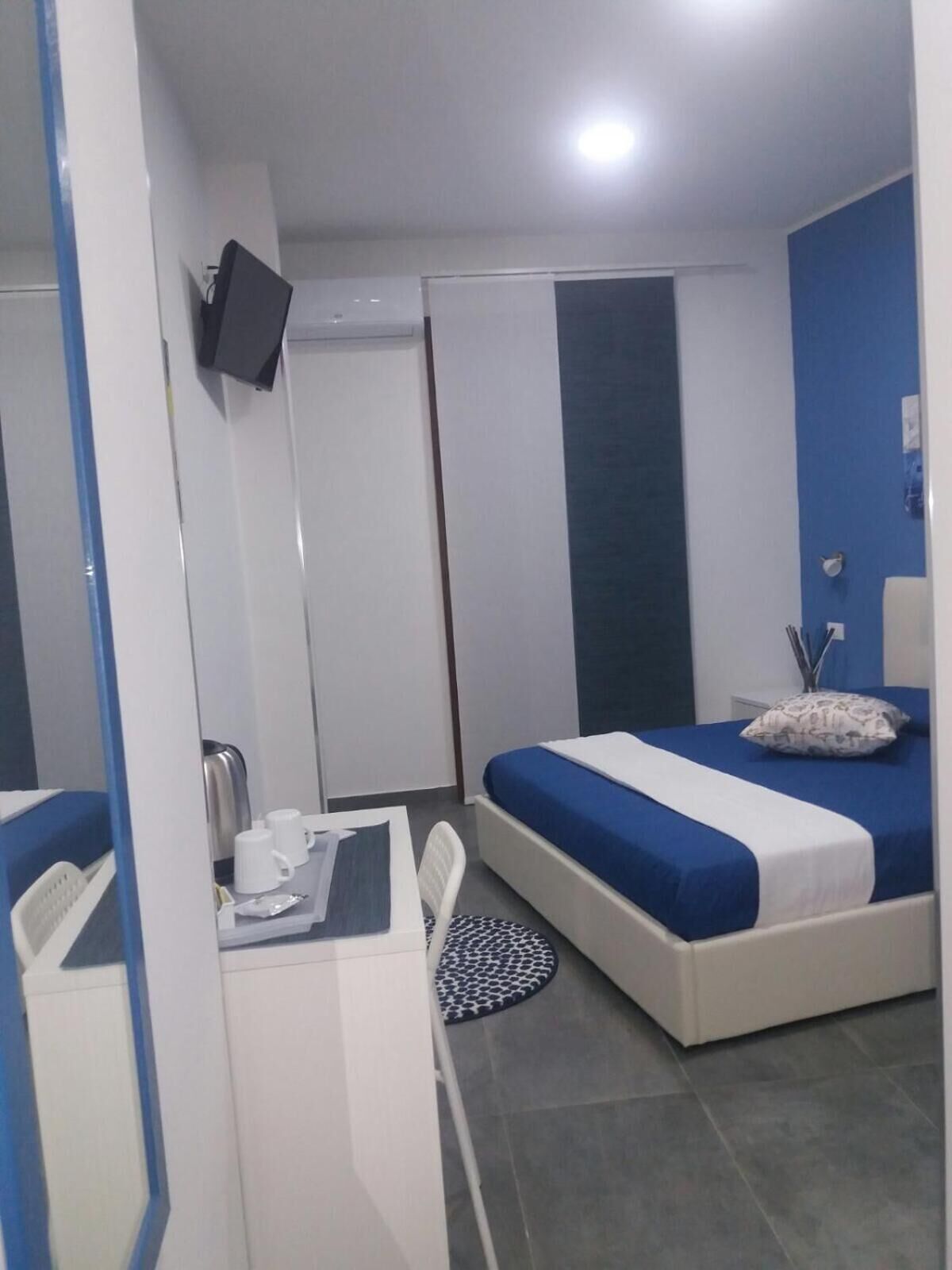 A bedroom with a bed, a desk, and a TV mounted on the wall.